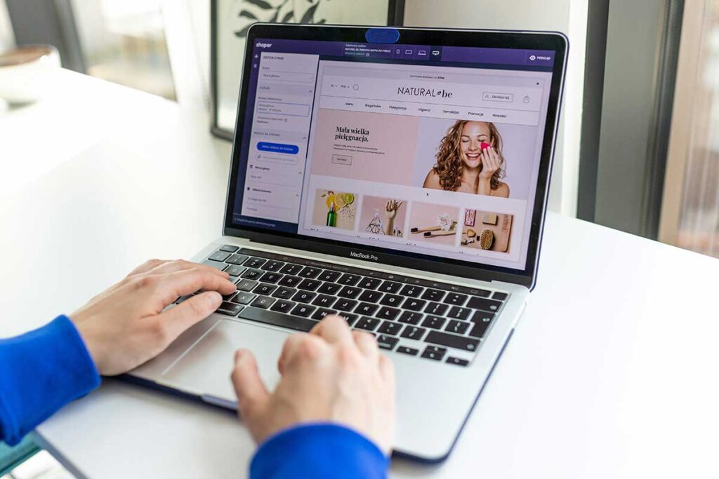 Person using a laptop to manage an online store with an e-commerce website displayed on the screen.